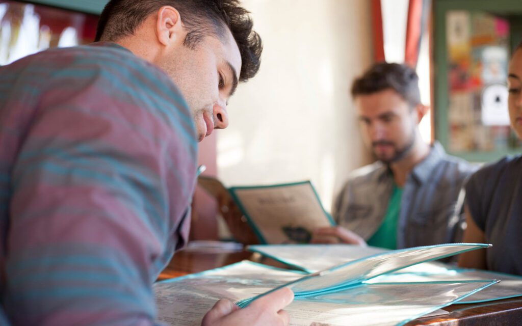 Varios jóvenes sentados a la mesa de un restaurante consultando el menú