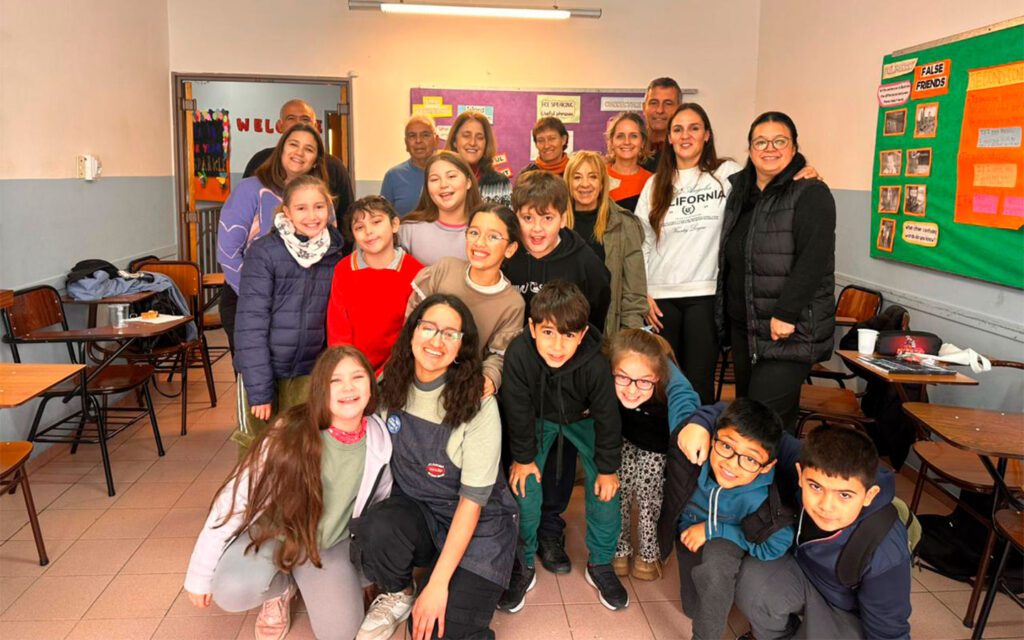 Grupo de niños y adultos posando sonrientes en un aula de clases