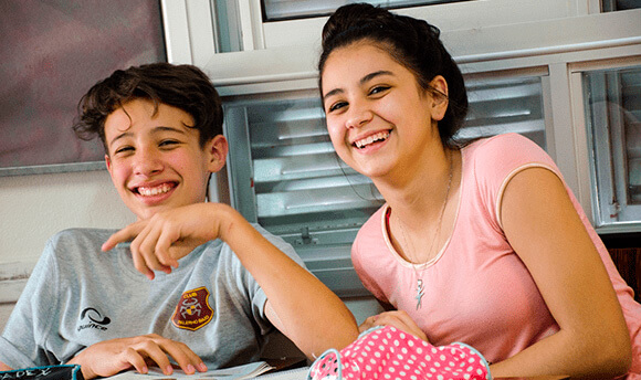 Dos adolescentes sonriendo sentados en un aula